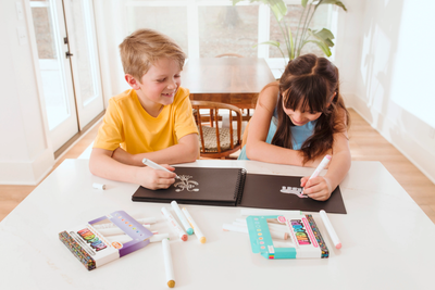 Two-kids-coloring-on-black-paper-pad-with-OOLY-Vivid-Pop-Paint-Markers-wide-shot_04c3982b-0293-41c1-a9d1-7f1270781dec.png